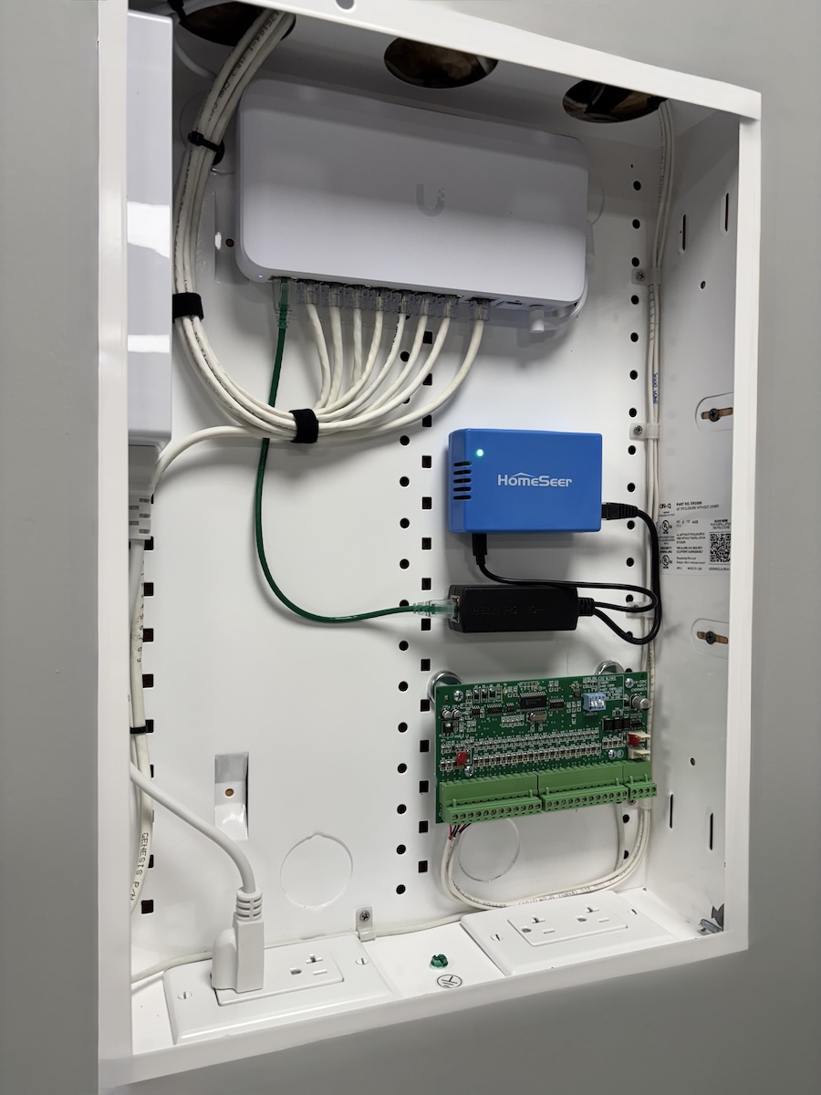 In-wall network enclosure with switch, alarm expansion panel, and home automation hardware.